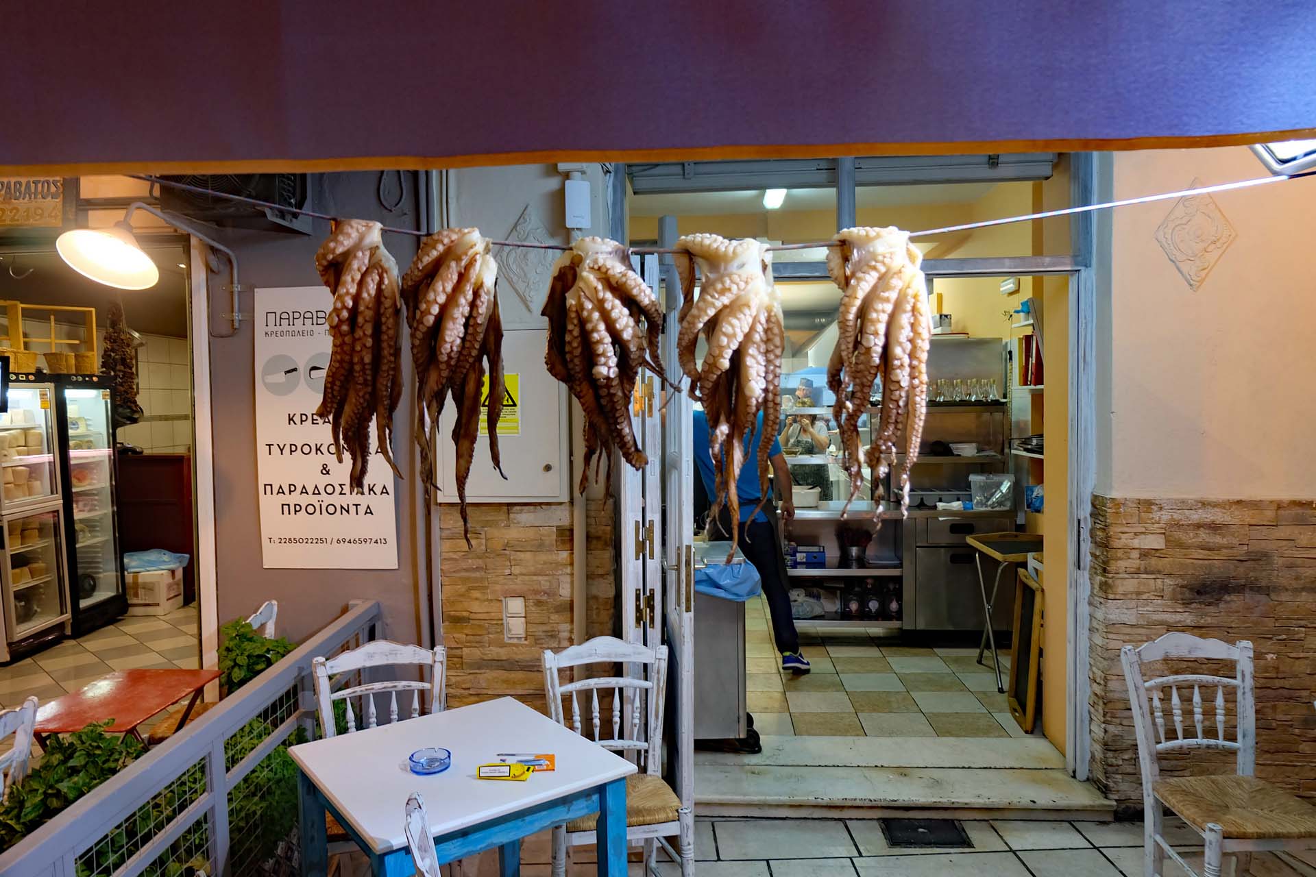 Frischer Octopus haengt zum Trocknen auf einer Leine vor einer Taverne