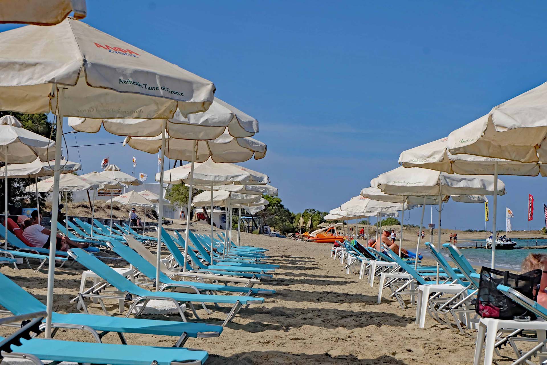 Sonnenliegen und -Schirme am Strand von Agios Georgios